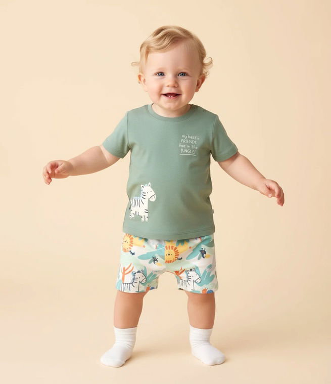 bebe em pé, com meia branca e blusa verde de zebrinha